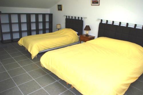 2 Betten mit gelber Bettwäsche in einem Schlafzimmer in der Unterkunft Gite le Mas de l'Amandier in Saint-Saturnin-lès-Avignon