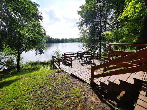 a wooden dock with tables and benches next to a lake at Urocza Przystan in Kiemiany