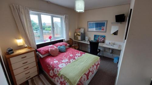 een slaapkamer met een bed, een bureau en een raam bij Tennyson Lodge in Mablethorpe