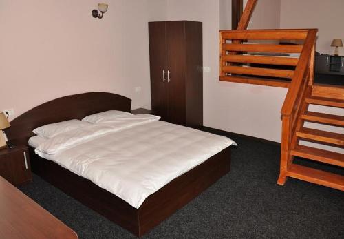 a bedroom with a bed and a wooden ladder at Pensiunea Valcinet in Borşa