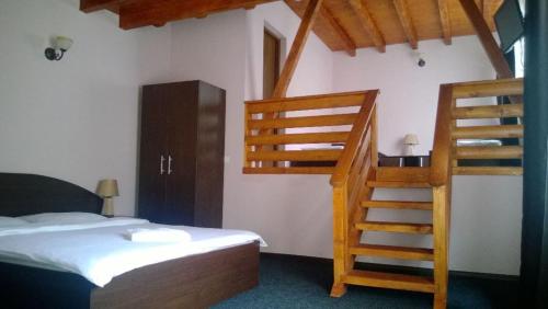 a bedroom with a bed and a wooden staircase at Pensiunea Valcinet in Borşa