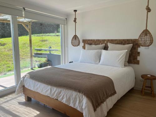 a bedroom with a large bed and a large window at Azores 5 estrelas in Porto Judeu