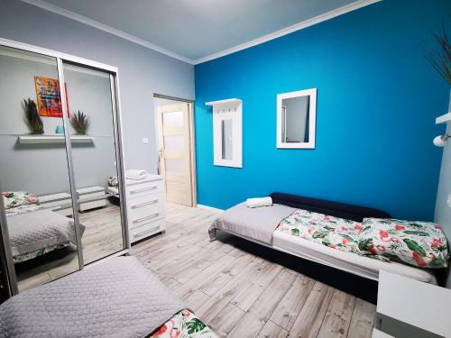 a blue bedroom with a bed and a mirror at Urocza Przystan in Kiemiany