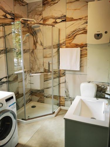 a bathroom with a shower and a washing machine at Urocza Przystan in Kiemiany