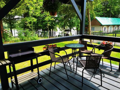 a porch with chairs and a table and a table at Urocza Przystan in Kiemiany