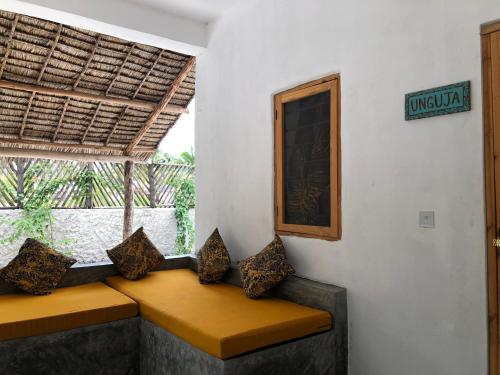a bench with pillows sitting in a room with a window at BONDENI BEACH HOUSE in Jambiani