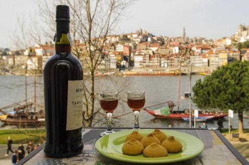 uma garrafa de vinho e um prato de comida e copos de vinho em Douro River Apartments em Vila Nova de Gaia
