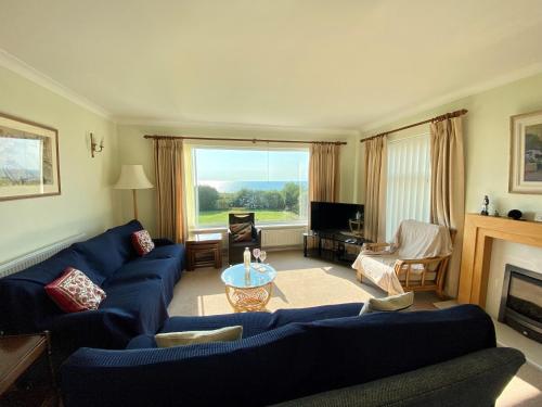 a living room with blue couches and a fireplace at Sea View 5 Bed House Next To Water Sports & Golf in Porthcawl