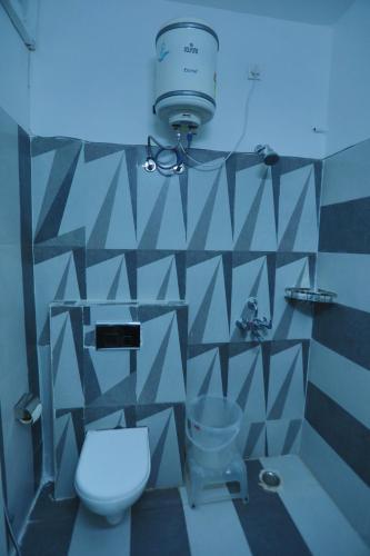 ein Badezimmer mit Toilette und Licht an der Wand in der Unterkunft FabHotel The Glory in Rishikesh