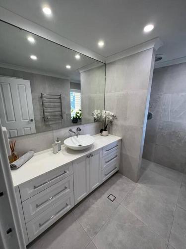 a bathroom with a sink and a large mirror at STUNNING! 'New York Style' Roof Top 2 Car Apartment in Perth