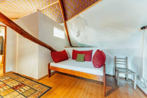 a room with a bench with red pillows and a chair at Utupoa in Matemwe