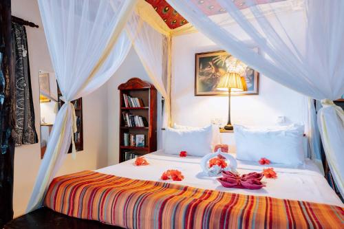 a bedroom with a bed with white curtains and flowers on it at Utupoa in Matemwe