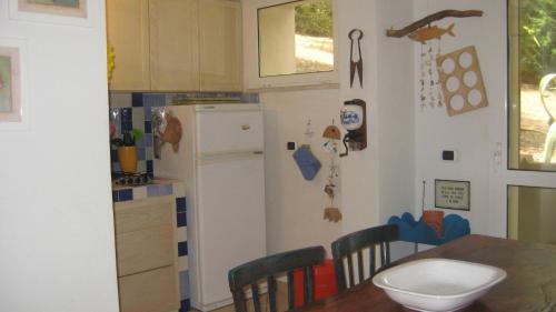 a kitchen with a table and a white refrigerator at Holiday Home La Quiete in Alghero