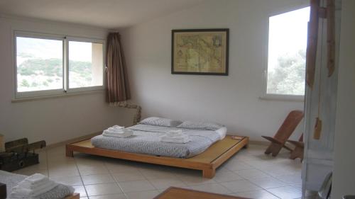 a bedroom with a bed and two windows at Holiday Home La Quiete in Alghero