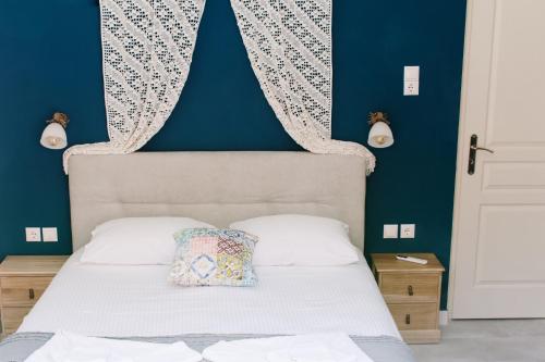 Un dormitorio con una cama blanca con una pared azul. en Antia House - Syros, en Ermoupoli