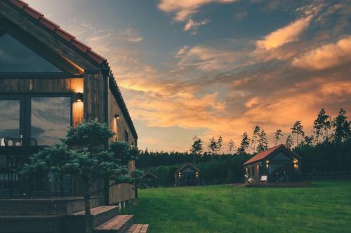 a barn with a sunset in the background at Mazurskie Hytte in Łukta