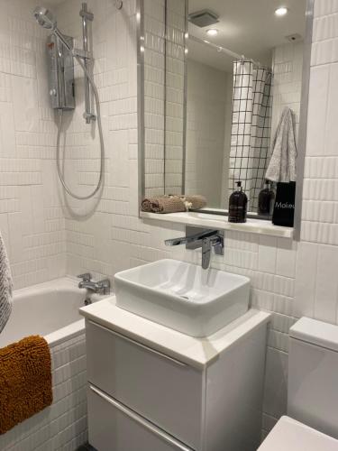 a white bathroom with a sink and a bath tub at Leith Street Suite in Edinburgh