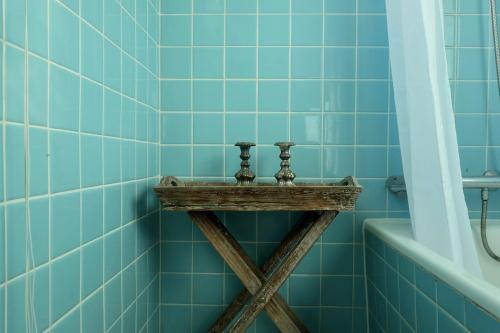 a blue tiled bathroom with a wooden shelf next to a bath tub at Hotel Strandlyst Badehotel in Hirtshals