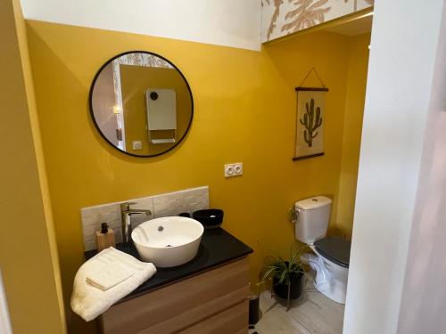 a yellow bathroom with a sink and a mirror at La Chaise Haute in Hagetmau