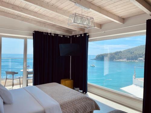 Schlafzimmer mit einem großen Fenster mit Blick auf das Wasser in der Unterkunft Ionian Terrace in Himarë