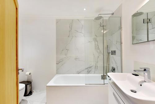 een witte badkamer met een douche en een wastafel bij London Choice Apartments - Chelsea - Sloane Square in Londen
