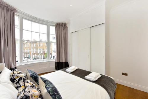 um quarto com uma cama e uma grande janela em London Choice Apartments - Chelsea - Sloane Square em Londres