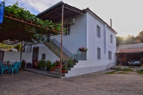 een wit huis met een trap en een tafel en stoelen bij Skadar Lake House in Bar