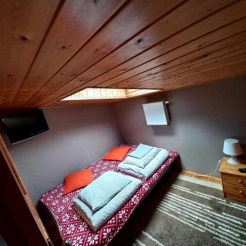 a bed in a small room with a wooden ceiling at Jaśminowa Przystań in Stegna