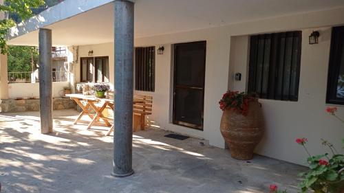 a porch of a house with a table and a vase at VillaTzer - Traditional house with fireplace and garden in Tzermiádon