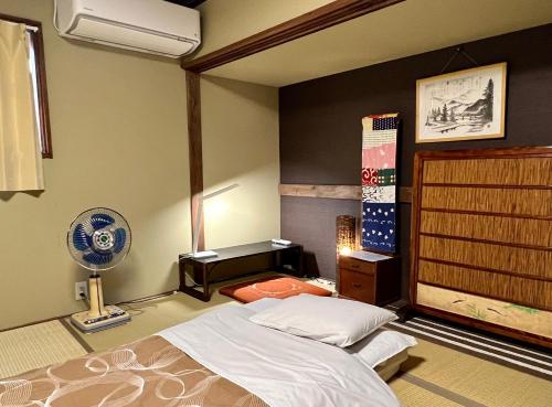 a bedroom with a bed and a desk and a fan at Guesthouse Naramachi in Nara