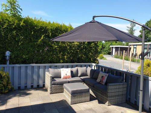 a patio with a couch and an umbrella at Vintage stacaravan Fereale Grou in Grou