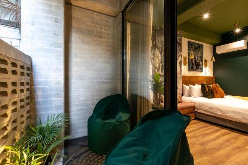 a room with a bed and two green chairs at Celestino Boutique Hotel & Spa in Medellín