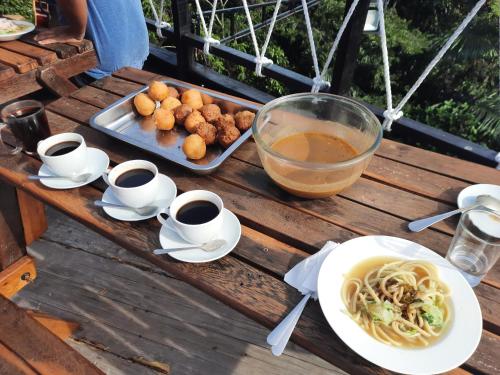 una mesa con una bandeja de comida y tazas de café en The Boat Homestay and Spa, en Balige