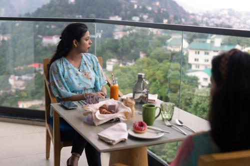 a woman sitting at a table with a plate of food at The Oasis Mussoorie - A Member of Radisson Individuals in Mussoorie
