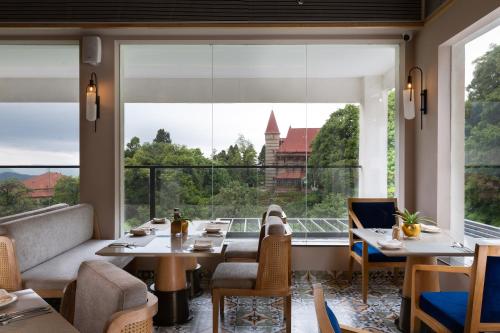a restaurant with tables and chairs and a large window at The Oasis Mussoorie - A Member of Radisson Individuals in Mussoorie