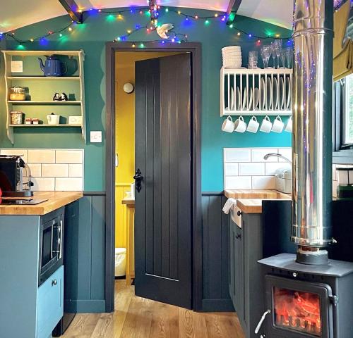 a kitchen with a stove in a kitchen with lights at Old King William Shepherd Huts and Private Hot Tubs in North Norfolk in Hunworth