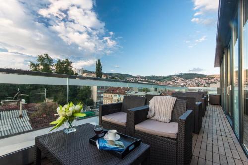 a balcony with chairs and a table with a view at City Boutique Hotel in Sarajevo