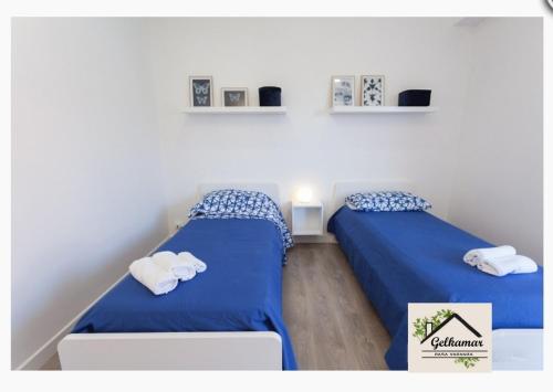 two beds in a room with blue sheets and towels at Gelkamar Apartment in Santa Flavia