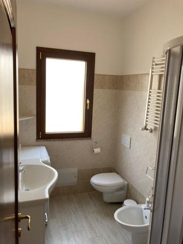 a bathroom with a sink and a toilet and a window at Smeralda in Olbia