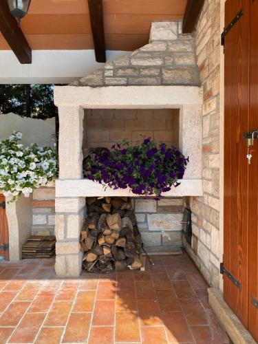 a stone fireplace in a patio with purple flowers at Villa Eva Karigador in Novigrad Istria