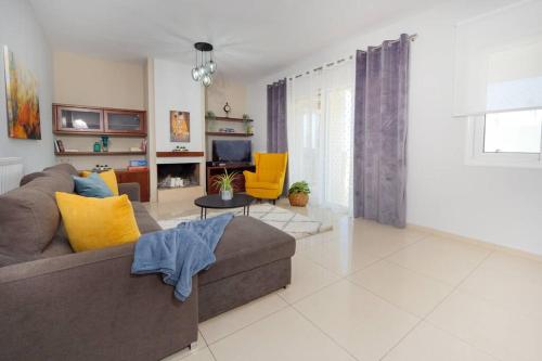 ein Wohnzimmer mit einem braunen Sofa und gelben Kissen in der Unterkunft GPK Bright & Stylish 4BR - Central with Free Parking in Iraklio