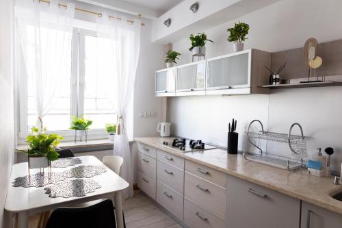 a kitchen with white cabinets and a table with plants at ClickTheFlat Szkolna Palace of Culture Apart Rooms in Warsaw