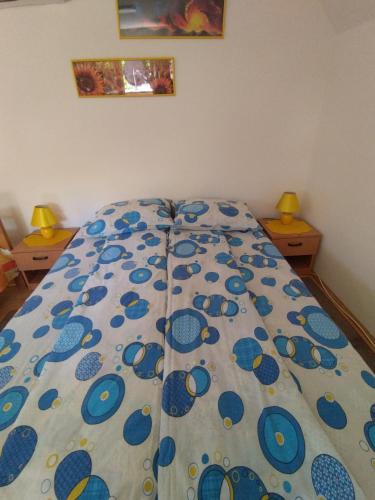 a bed with a blue flowered comforter in a bedroom at Apartmani Bubamara in Soko Banja