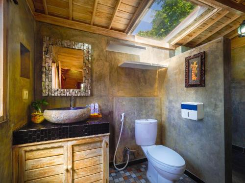 a bathroom with a toilet and a sink and a mirror at Wisnu Lumbung Uluwatu in Uluwatu