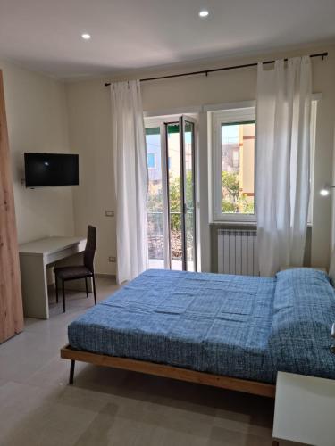 ein Schlafzimmer mit einem blauen Bett, einem Schreibtisch und einem Fenster in der Unterkunft Casa Sofia in Gaeta