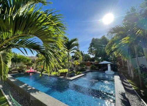 a swimming pool with palm trees next to a building at Halamanan Residences in Panglao