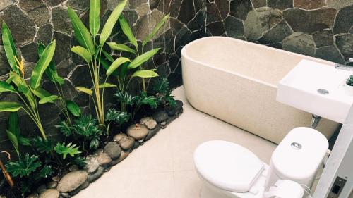 a bathroom with a toilet and a sink and plants at Villa Tjokro in Yogyakarta