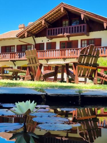 a house with chairs and a lily in a pond at Hotel La Cumbrecita in La Cumbrecita