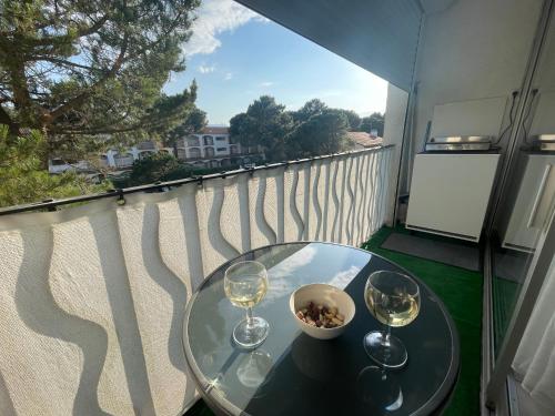 un tavolo con due bicchieri di vino su un balcone di Nuria Superbe Meublé 3* avec loggias 250m des plage a Plage dʼArgelès