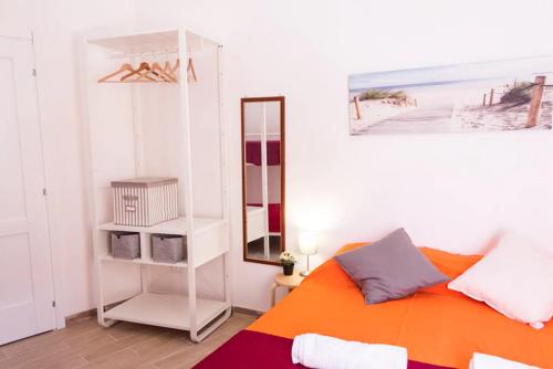 1 dormitorio con cama de color naranja y espejo en [DOWNTOWN SELINUS] Bright apartment with courtyard en Marinella di Selinunte